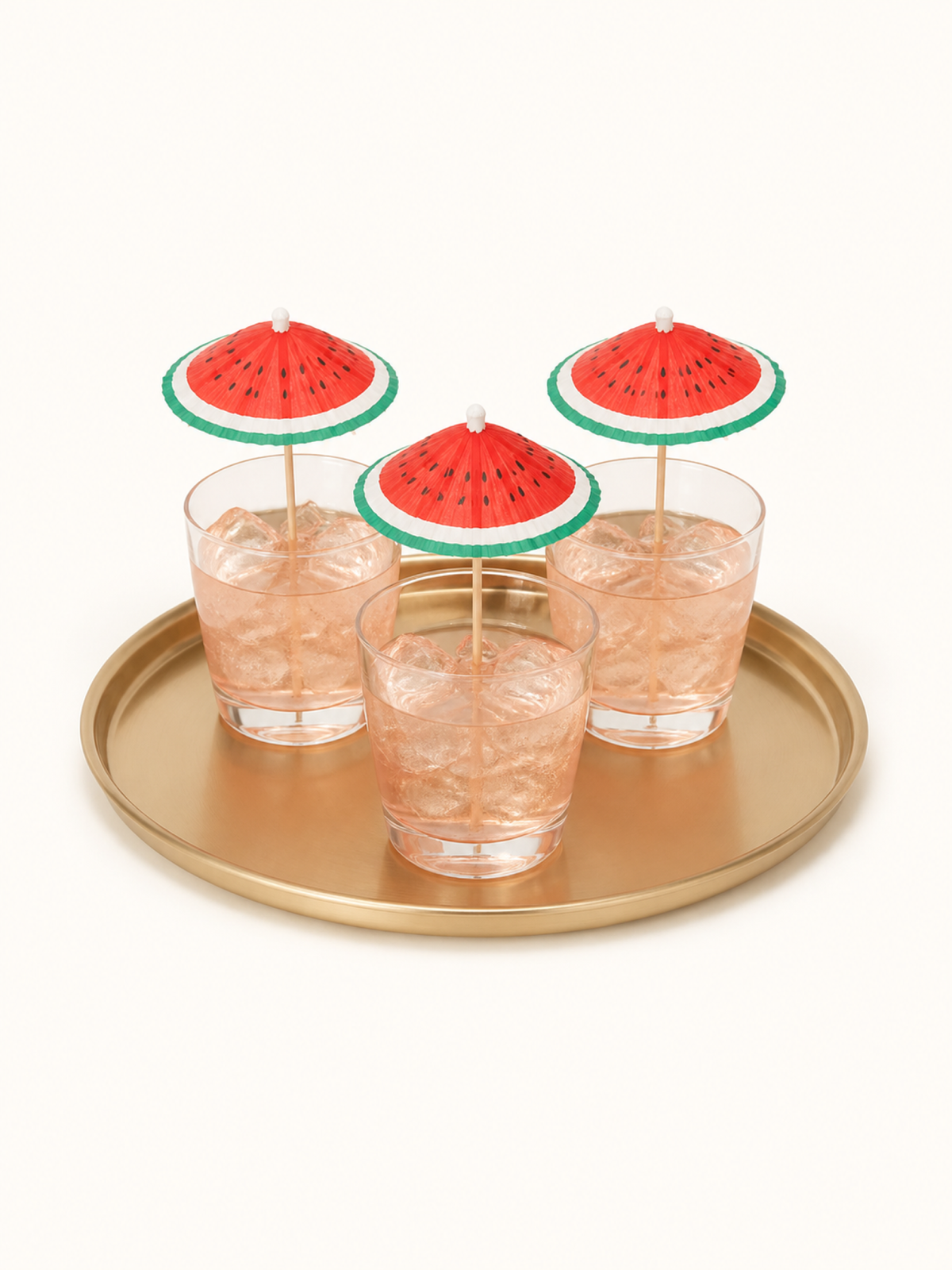 Watermelon cocktail umbrellas in three iced drinks on a round tray